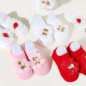 Close-up of baby floral headband and knit socks set in white, pink, and red colors