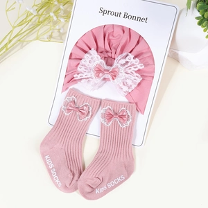 Pink baby bonnet with lace and matching socks featuring bows and non-slip grips