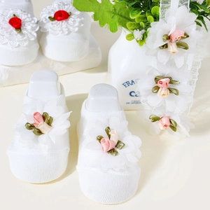Close-up of white baby cotton socks featuring delicate 3D floral lace and satin rose details