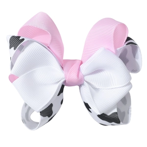 Detailed macro view of layered grosgrain bow hair clip with pink and cow print texture