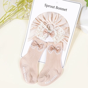 Detail of baby turban and ribbed socks with lace bows on a soft floral background