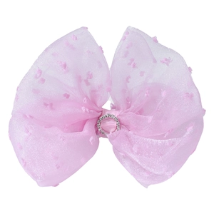 Close-up of a pink organza bow hair clip with velvet dots and a rhinestone center ring