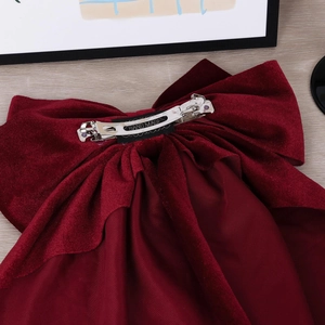 Detail of burgundy velvet bow hair clip with silver spring metal fastener and handmade label