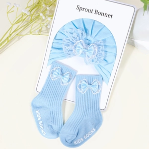Detail of light blue cotton baby hat and socks set with lace bows and rib texture