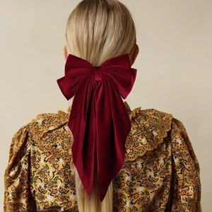Rear view of a large burgundy velvet bow hair clip with long ribbons on wavy hair