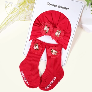 Detail of red cotton baby turban hat and socks set featuring delicate fabric flower accents
