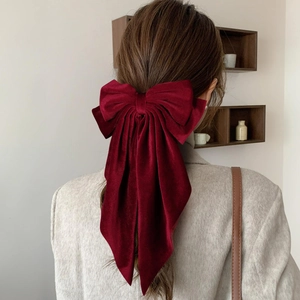 Detail view of a large burgundy velvet bow hair clip with long ribbons on hair