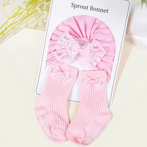 Close-up of pink baby sprout bonnet and matching lace bow socks set in soft cotton