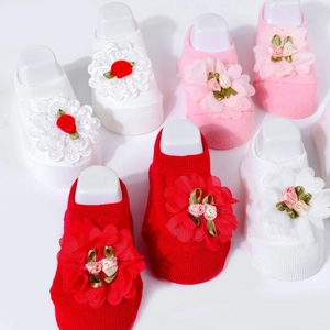Detail of baby socks with lace floral decorations in white, pink and red colors
