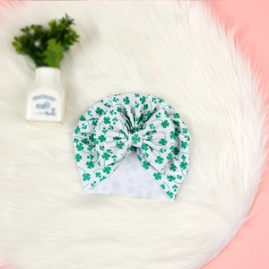 Détail d'un bonnet turban blanc pour bébé avec trèfles verts et grand nœud soigné