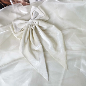 Macro detail of cream velvet hair clip showing texture and double bow with long ribbons