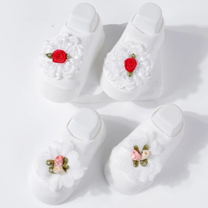 Close-up of baby knit socks featuring delicate handmade red and pink floral decorations