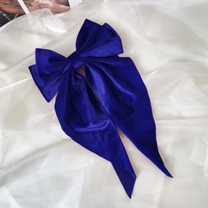 Detailed texture of royal blue velvet bow hair clip with elegant long ribbons and satin gloss