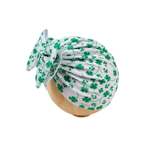 Détail du motif trèfle vert sur turban pour bébé en tissu gaufré blanc avec nœud