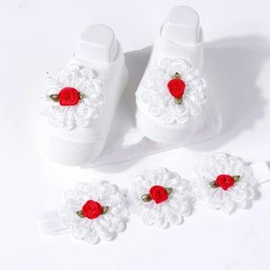 Close-up of baby socks and headband with white lace petals and red silk ribbon roses