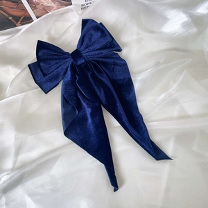 Detail of deep blue velvet hair bow showing soft texture and long elegant ribbons