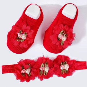 Detail of red baby flower headband and cotton socks with 3D floral petals and green leaves