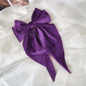 Detail of a luxury deep purple velvet bow hair clip with long flowing ribbons