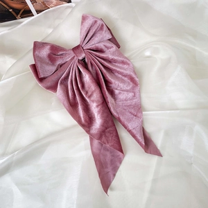 Detail of elegant dusty rose velvet bow hair clip with long ribbons on white tulle