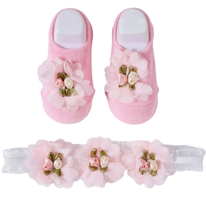 Detailed view of pink cotton baby socks and white lace headband with floral accents