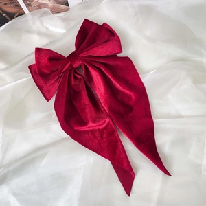 Detail of burgundy velvet oversized bow hair clip with long streamers on white silk