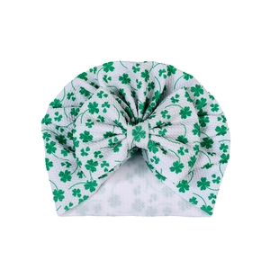 Détail du bonnet tricoté pour bébé avec motif trèfle vert et gros nœud décoratif