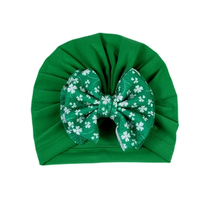 Détail du bonnet vert bébé avec grand nœud texturé et motif trèfle pour la Saint-Patrick