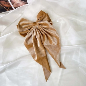 Detail of elegant champagne velvet bow hair clip with long ribbons on white tulle