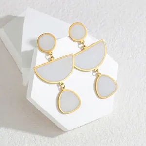 Minimalist geometric drop earrings featuring a gold frame and elegant matte white inlays