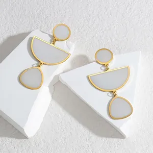 Elegant geometric gold drop earrings with grey matte inlay on artistic white marble blocks