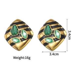 Detailed view of vintage asymmetric gold earrings with green stones and black enamel accents