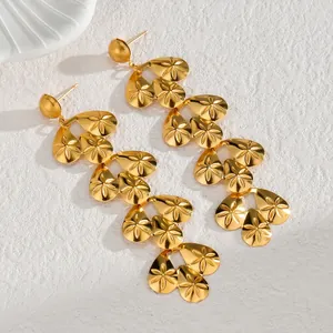 Long gold tassel earrings with teardrop leaf charms and floral engravings on white stone