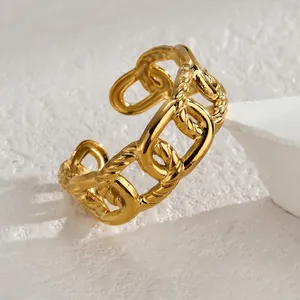 Detailed view of golden chain link ring featuring smooth and twisted textures on a pedestal