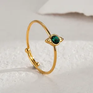 Close-up of gold stainless steel open ring with a round green gemstone in retro style