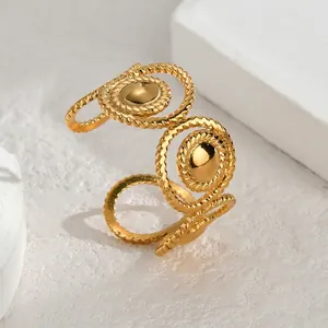 Detail of gold geometric braided ring with polished metal beads on textured stone