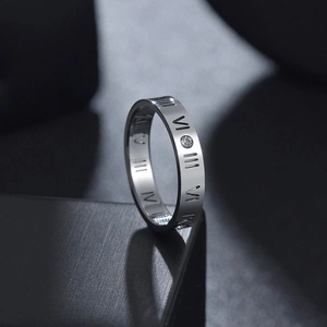 Vista de cerca de anillo plateado con números romanos y un diamante incrustado