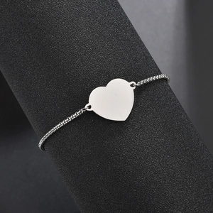 Bracelet avec pendentif cœur poli et chaîne gourmette fine sur présentoir minimaliste