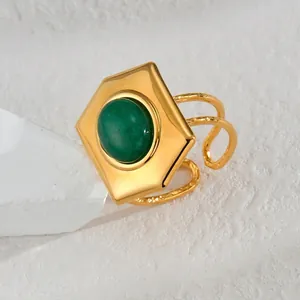 Elegant gold-polished stainless steel ring featuring a hexagonal green gemstone on white stone