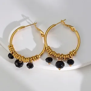 Créoles dorées bohèmes de style français avec perles noires sur un support blanc pur