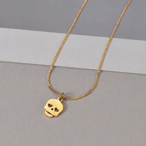Golden skull pendant necklace with heart-shaped eyes and polished finish on grey background