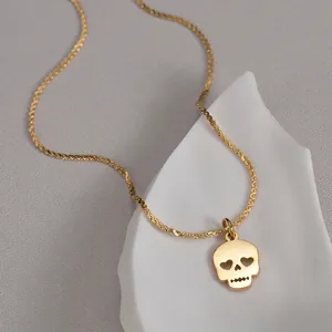 Polished gold skull pendant necklace with heart-shaped eyes on white ceramic plate