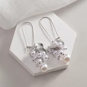 Elegant silver pearl cluster drop earrings with grape shape design on white marble stand