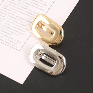 Close-up of gold and silver geometric rectangular hair clips with a metallic mirror finish