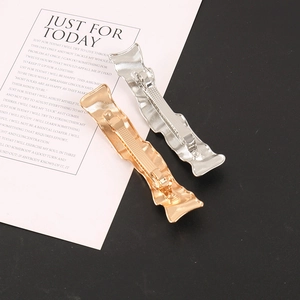 Detail of gold and silver wave-pattern metal hair clips with textured anti-slip design