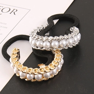 Detail of metal U-shaped chain hair tie with inlaid white pearls and black elastic rope