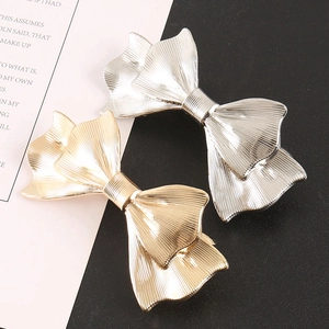 Close-up of gold and silver metal bow hair clips with radial texture and 3D structure