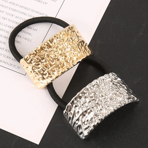 Dettaglio di elastici per capelli con accenti metallici martellati color oro e argento