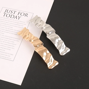 Detail of minimalist wavy metal hairpins in gold and silver finishes with mirror polish