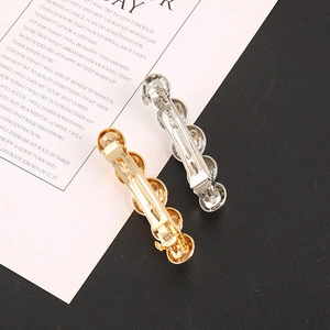 Detailed back view of gold and silver metal ball hair clips with spring mechanism