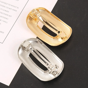 Detailed view of gold and silver hair clips with brushed texture and rectangular cutout